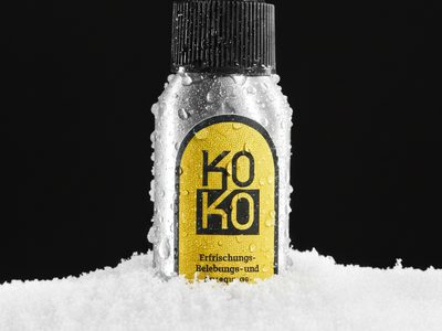 KoKo-Sprühflasche steht im Schnee vor schwarzem Hintergrund